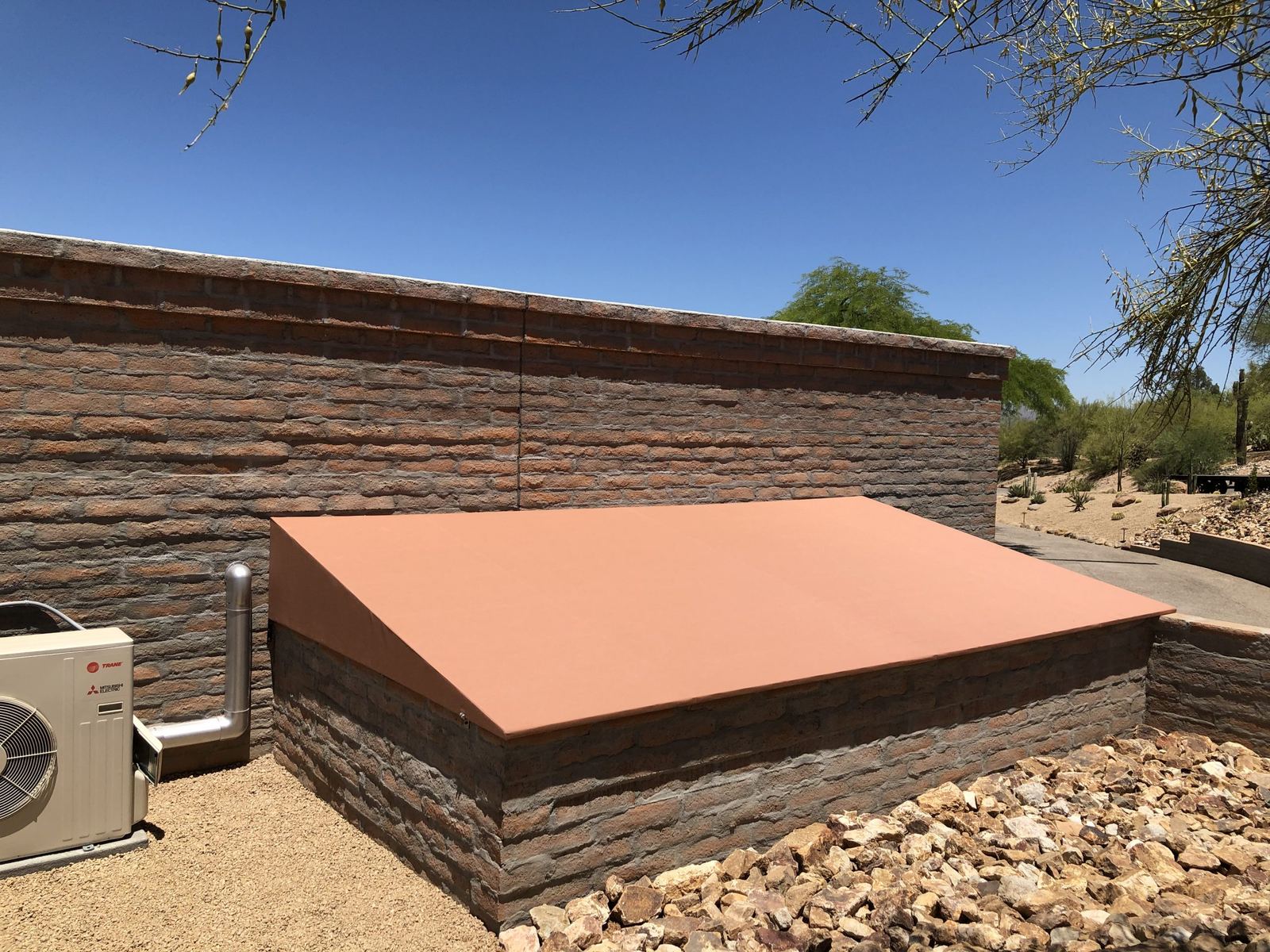 Freshly re-covered terracotta fabric awning fitted over a masonry structure in the high desert