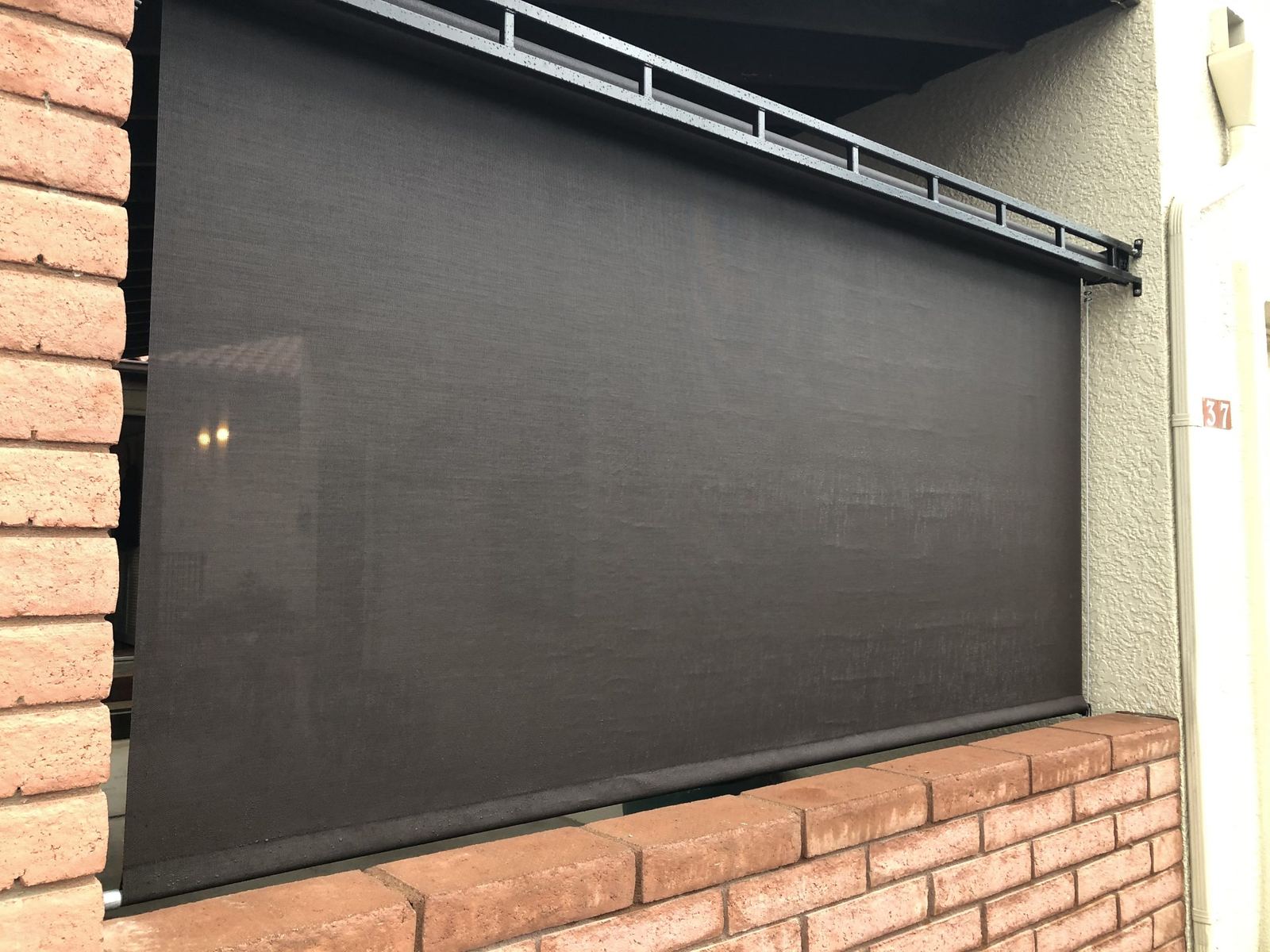 Exterior roller shade screen mounted over a patio opening